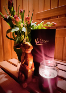 Świąteczna dekoracja w Saunie Olimpia – tulipany, świeca i figurka zająca w przytulnym wnętrzu sauny.